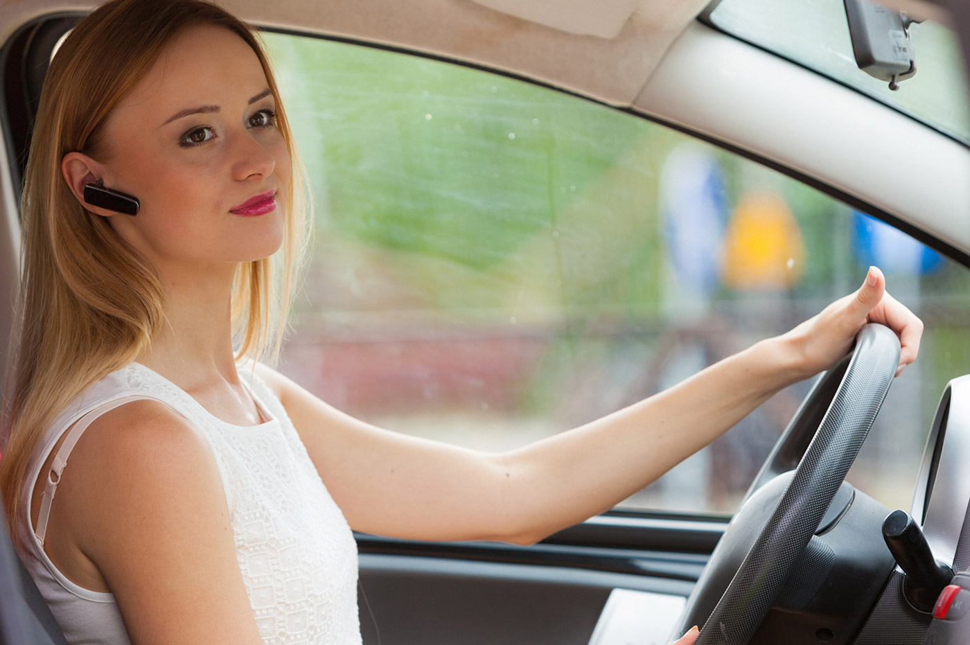 Woman using wireless headphones to make a call while driving.