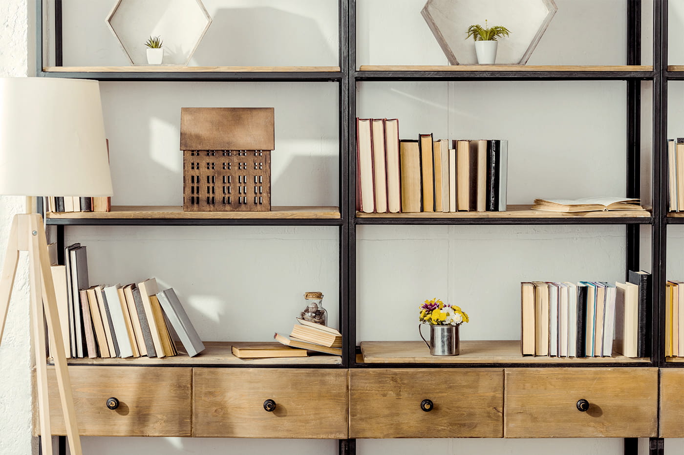 A light brown wooden bookshelf with books, plants, and some decorations.