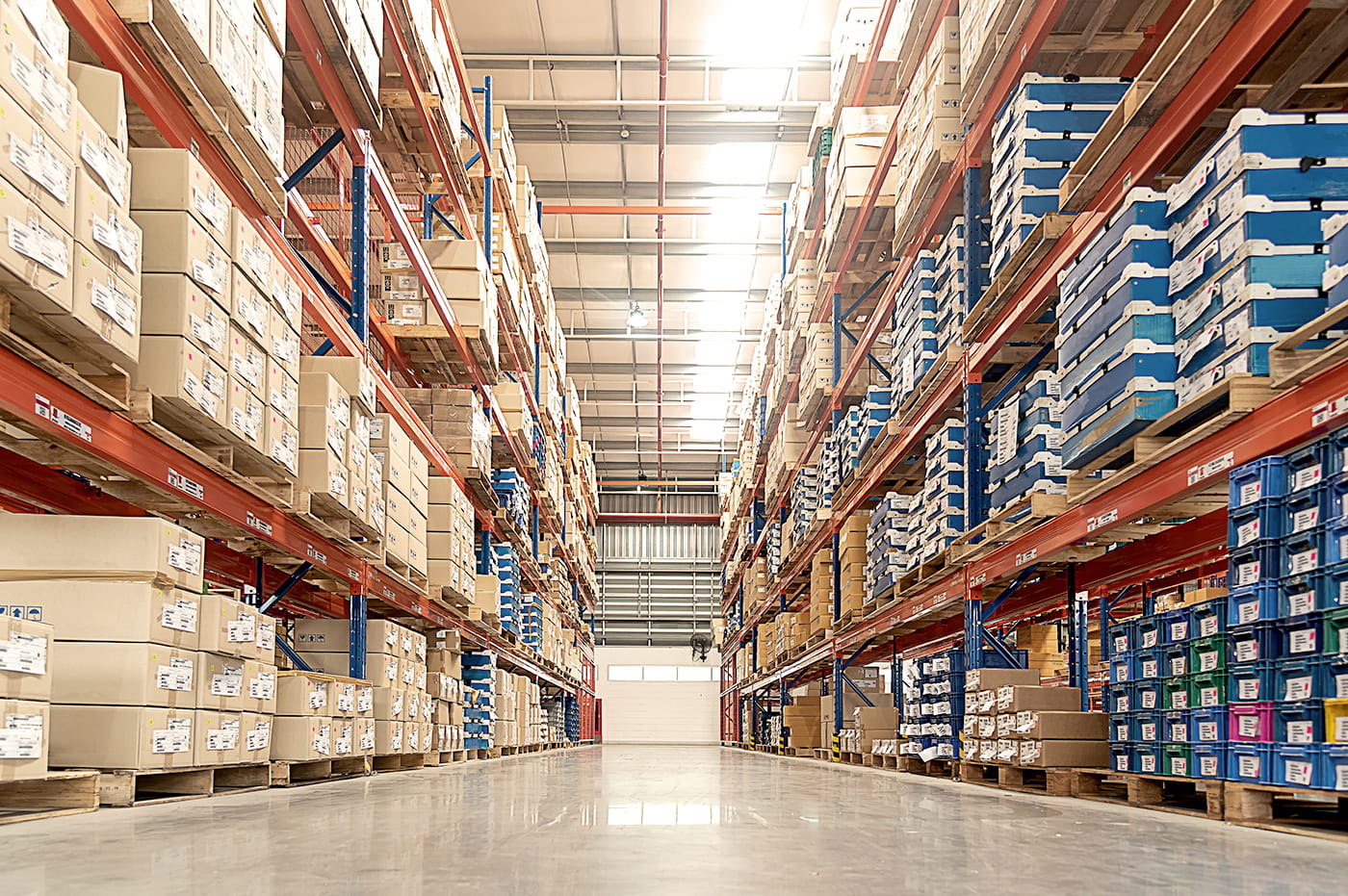 An aisle in a large warehouse with fully-stocked shelves.