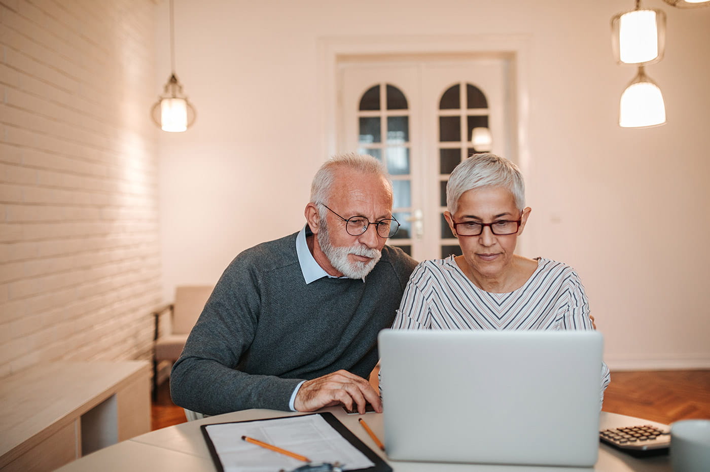 An older couple looking at a laptop toether.