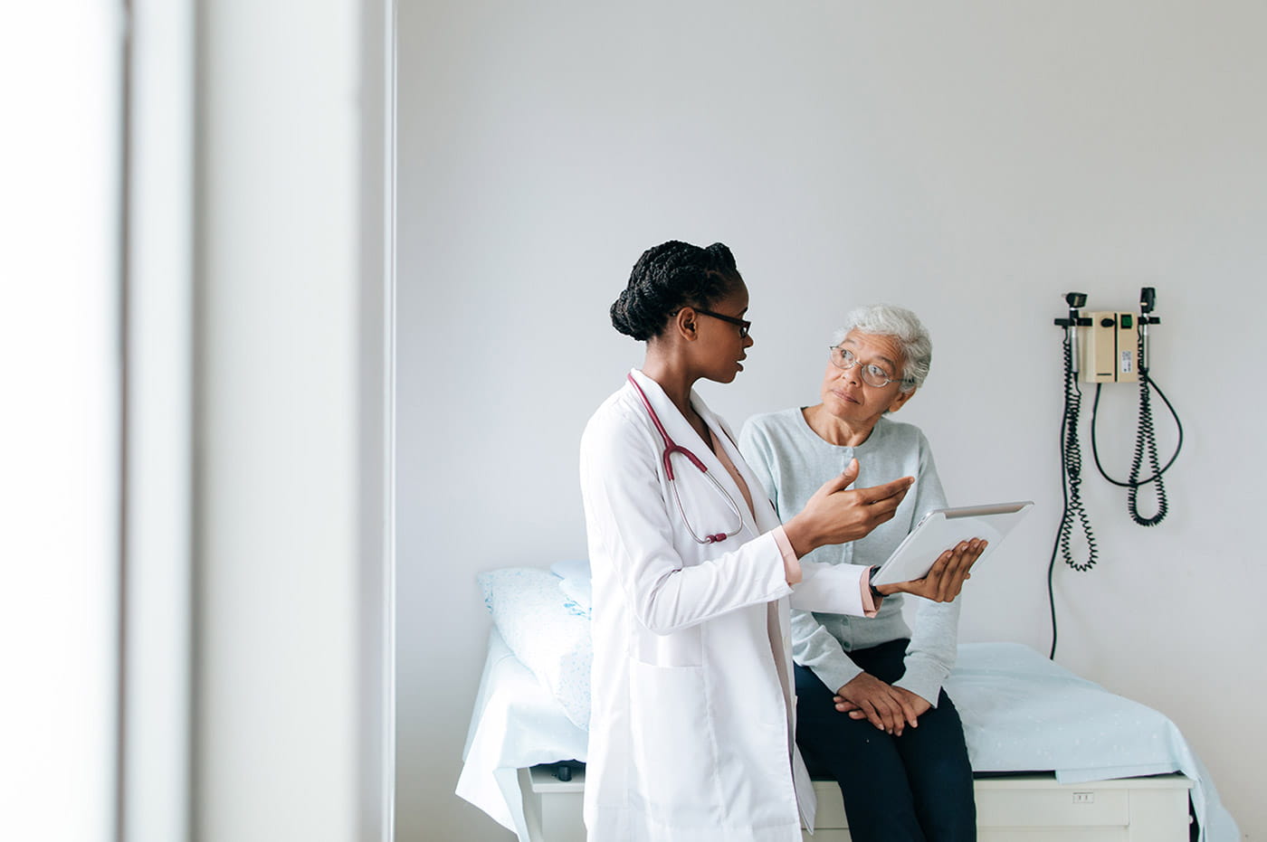 A female doctor reviewing information with her older patient.