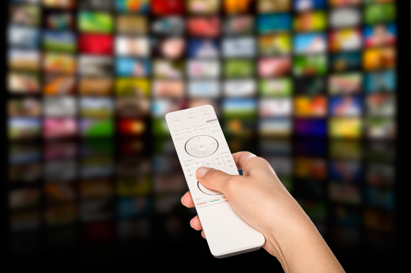 A remote pointed at a large screen with multiple options of shows and movies.