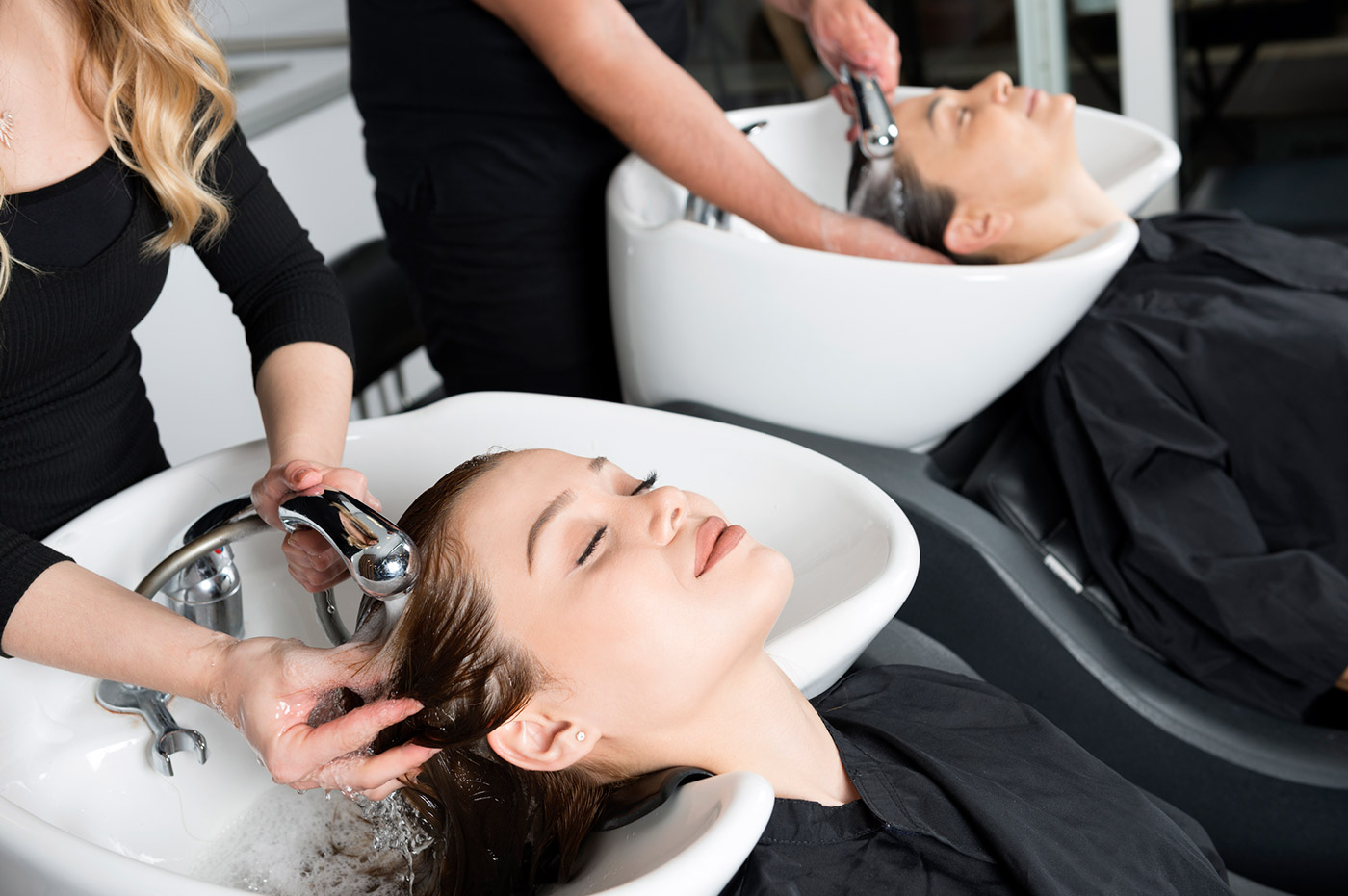 Two women getting their hair shampooed by hairdressers.