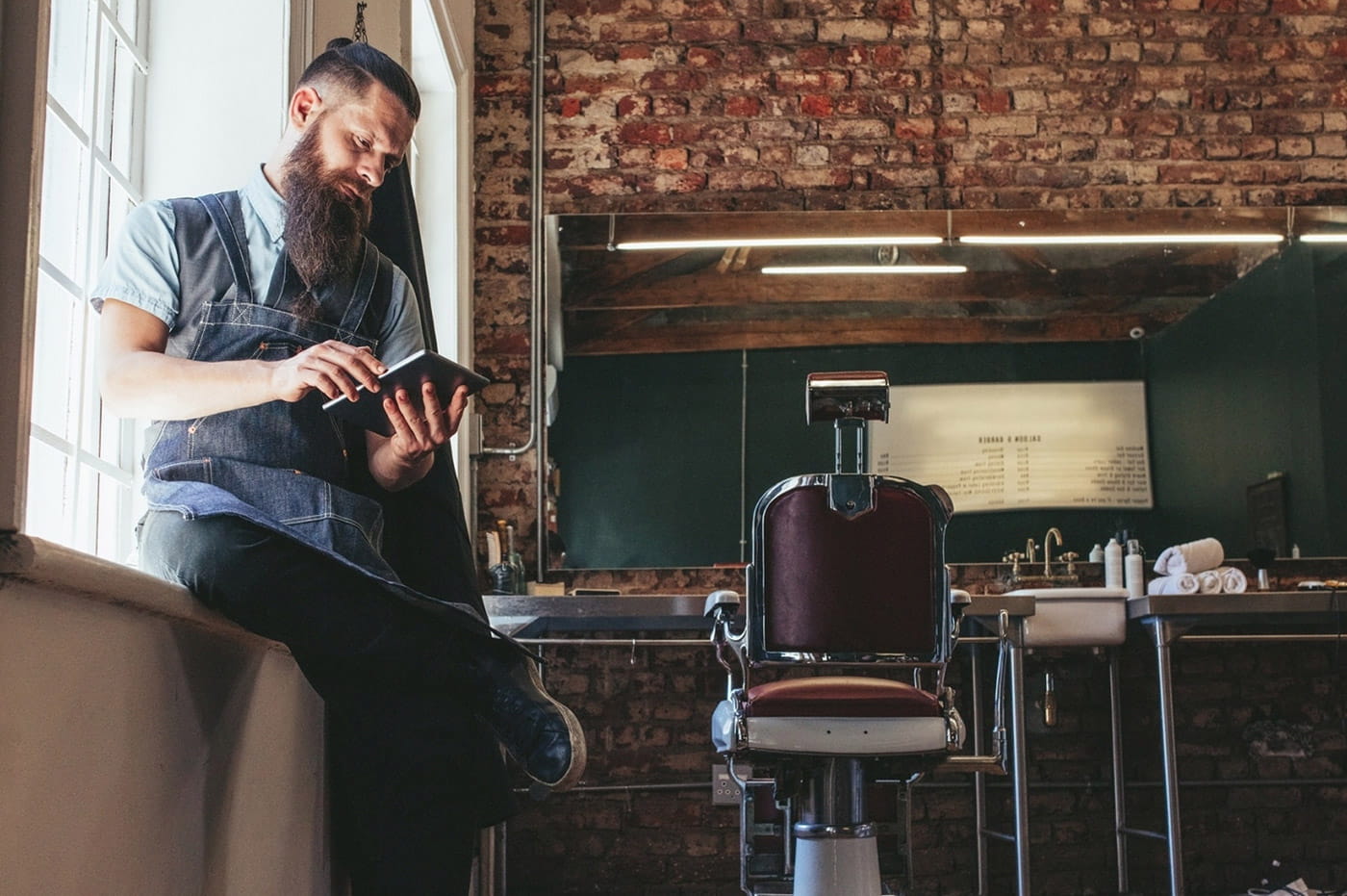 A hairdresser working on a tablet in his salon.