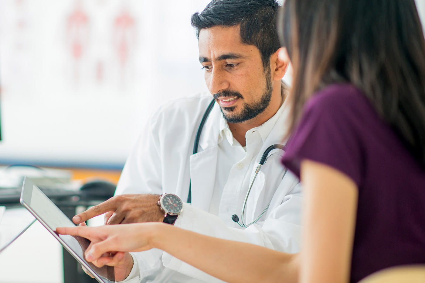 A doctor going over information displayed on a tablet with a woman.