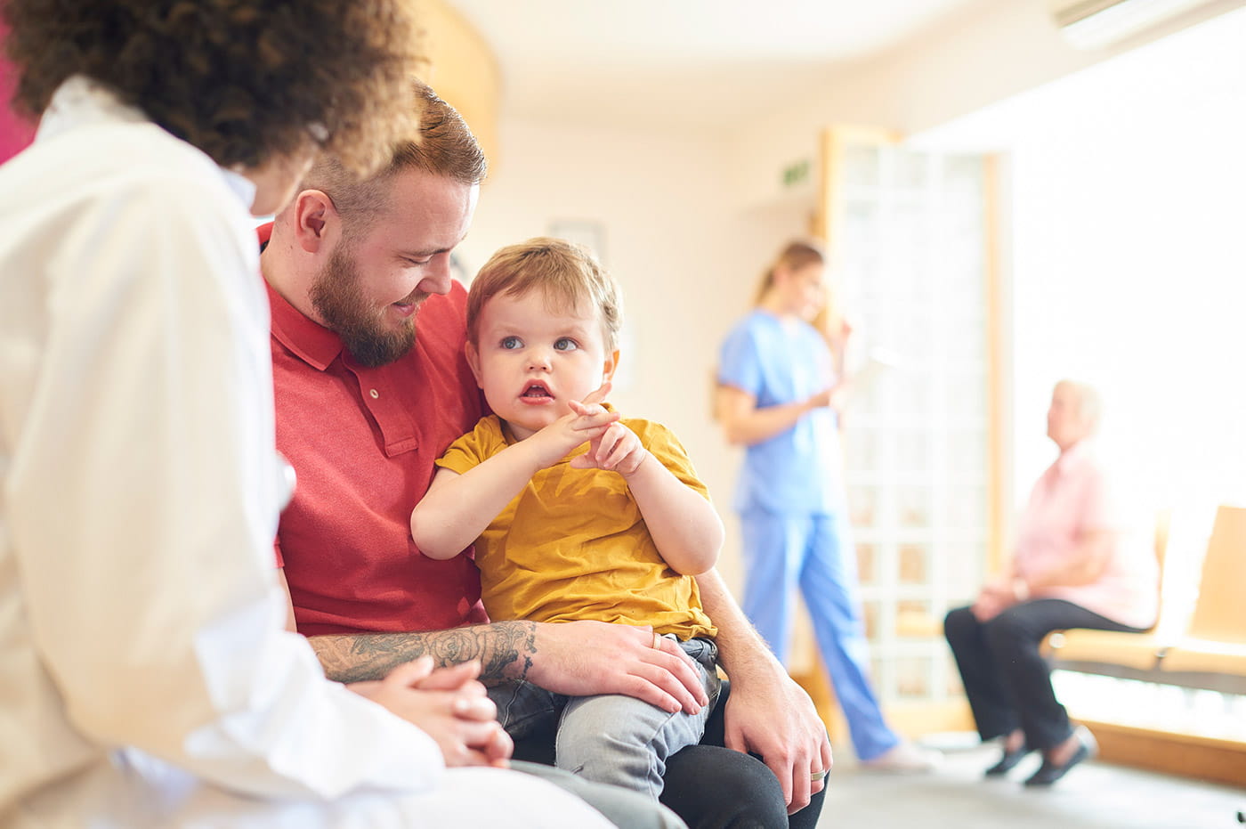 A doctor meeting with a baby being held by its dad.