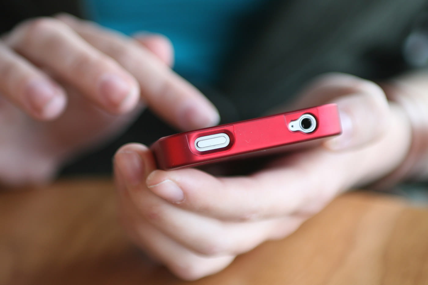 Power button and headphone jack for a red smartphone.