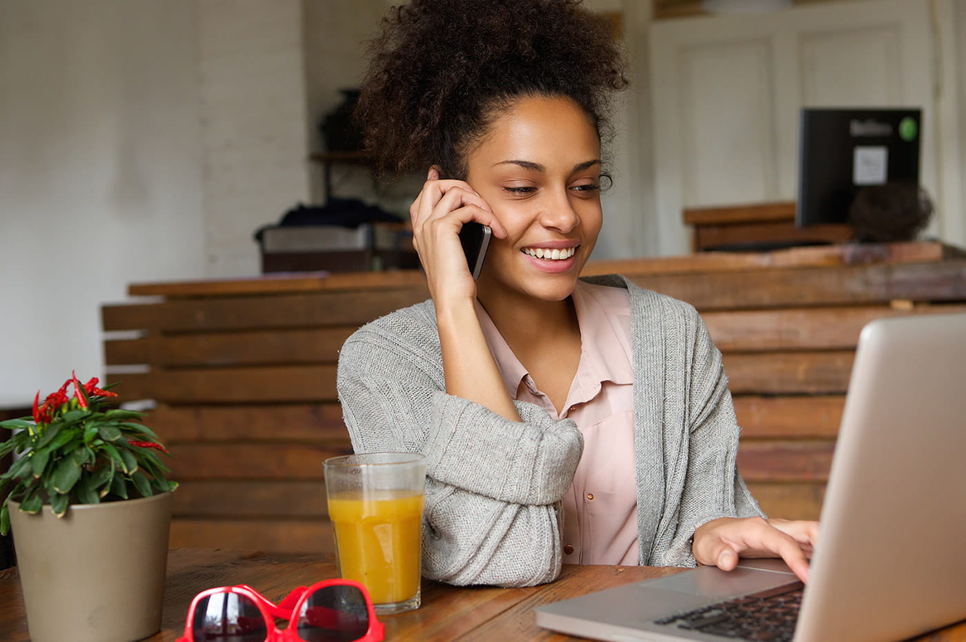 A young woman talking on the phone and working on her laptop.