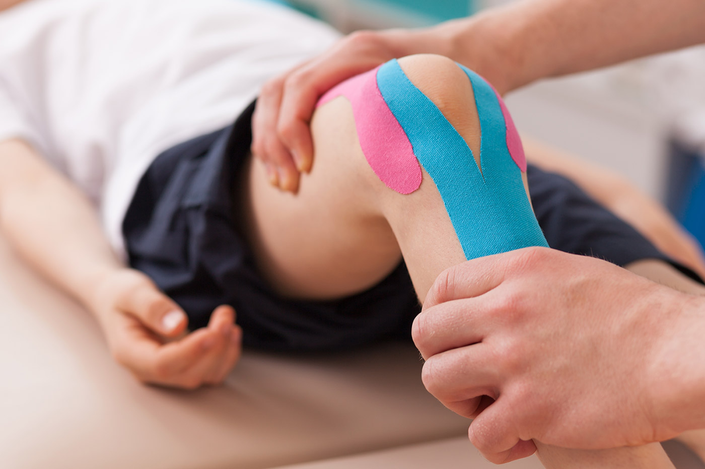 A knee bandaged with medical tape during physical therapy.