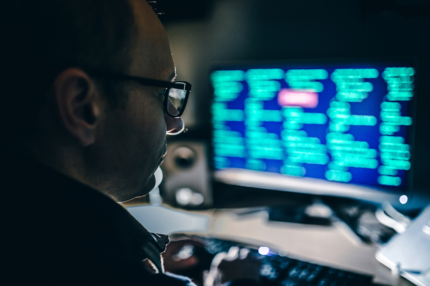 A man working on a large monitor in a dark office.