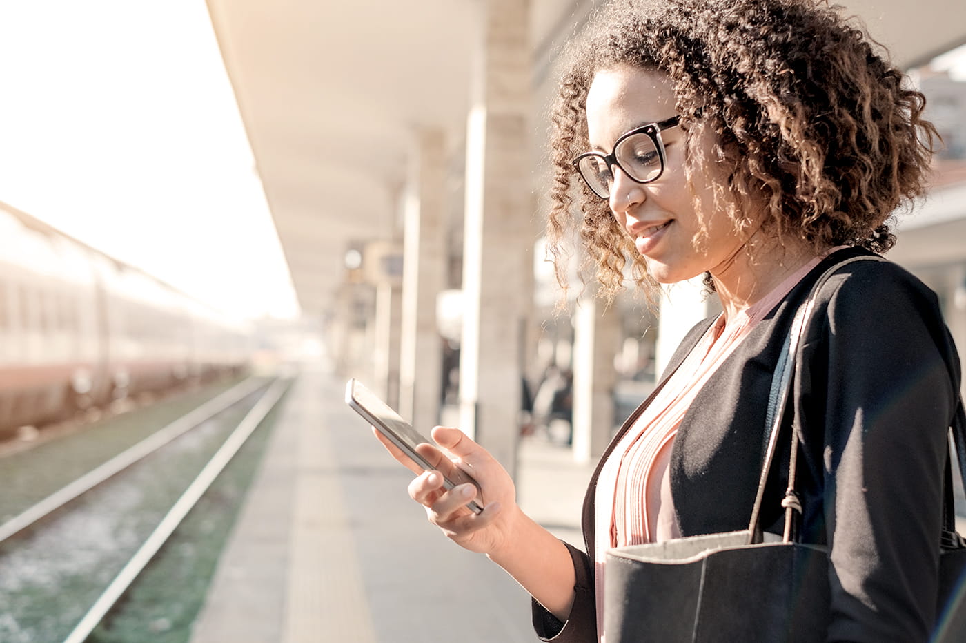 A woman working on a cellphone at a train station.