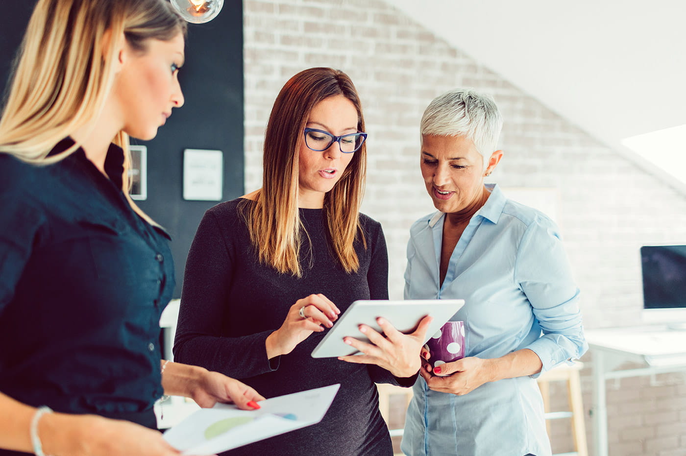 Three business women talking and looking at an iPad.