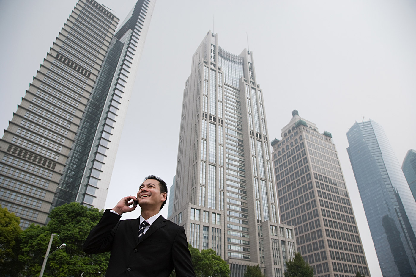A man talking on a cellphone in front of some skyscrapers.