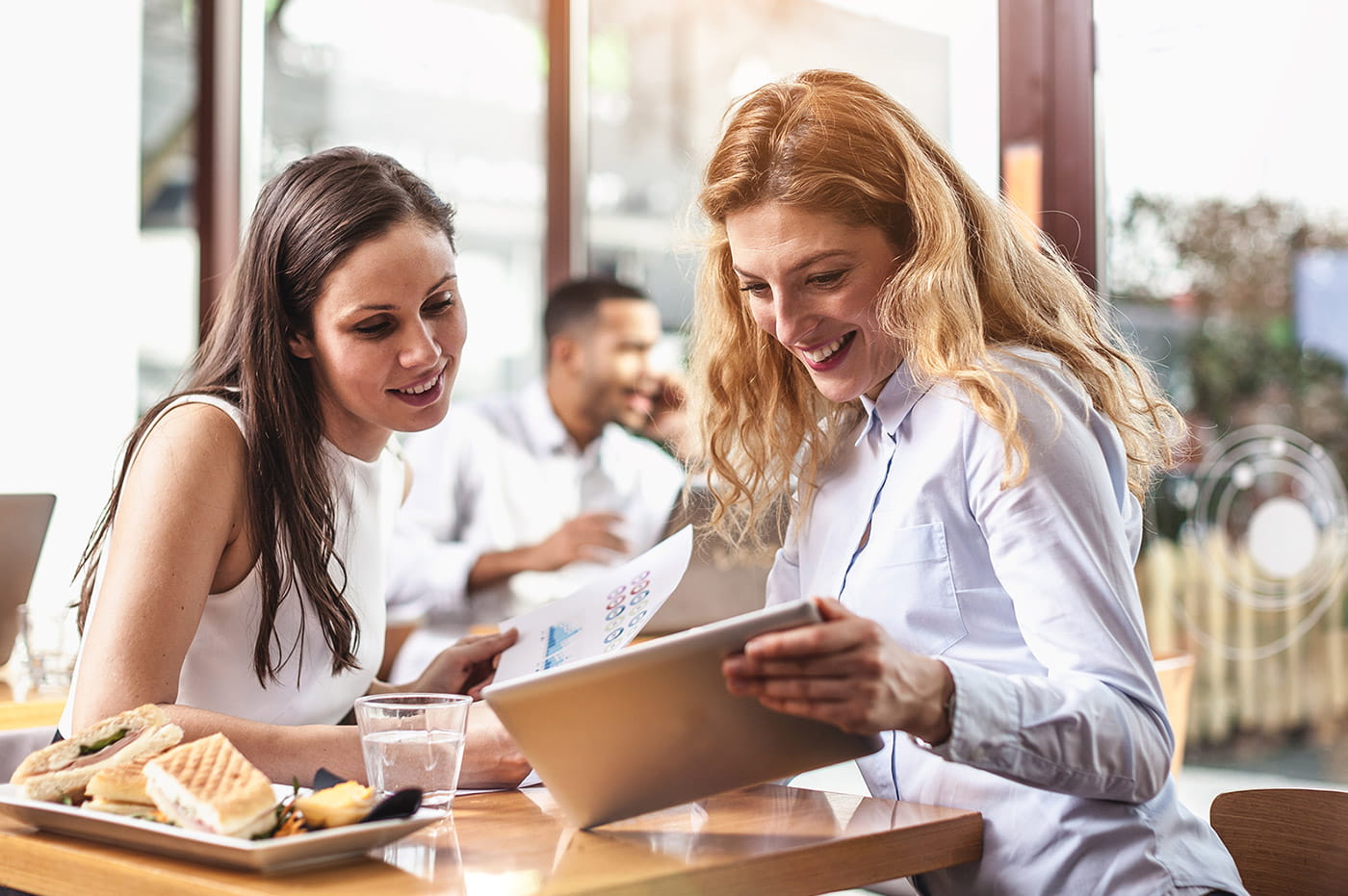 Two women working while eating lunch.