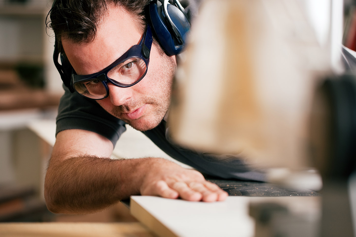 A man cutting a piece of wood using a rotator saw.