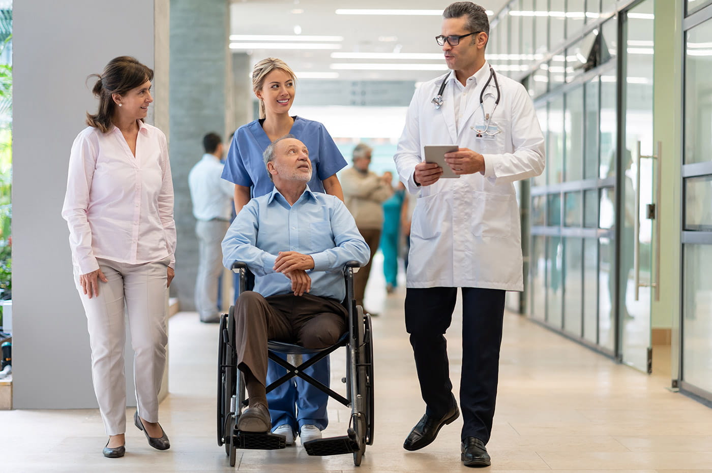 Three healthcare workers helping a one-legged man in a wheelchair.