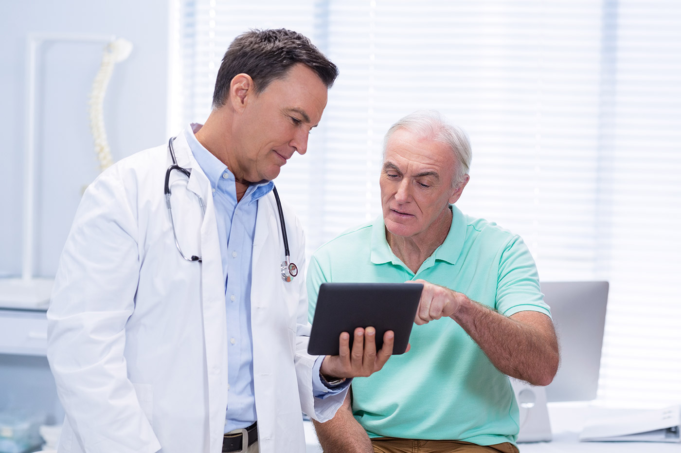 A doctor and patient reviewing information on a tablet.