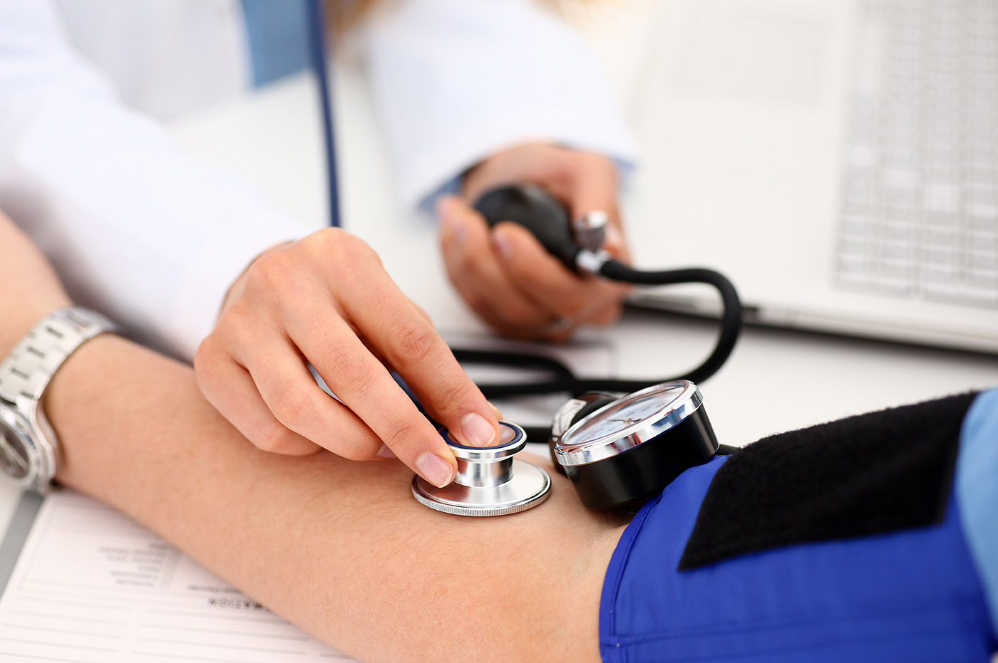 A doctor using a stethoscope and blood pressure cuff on a patient.