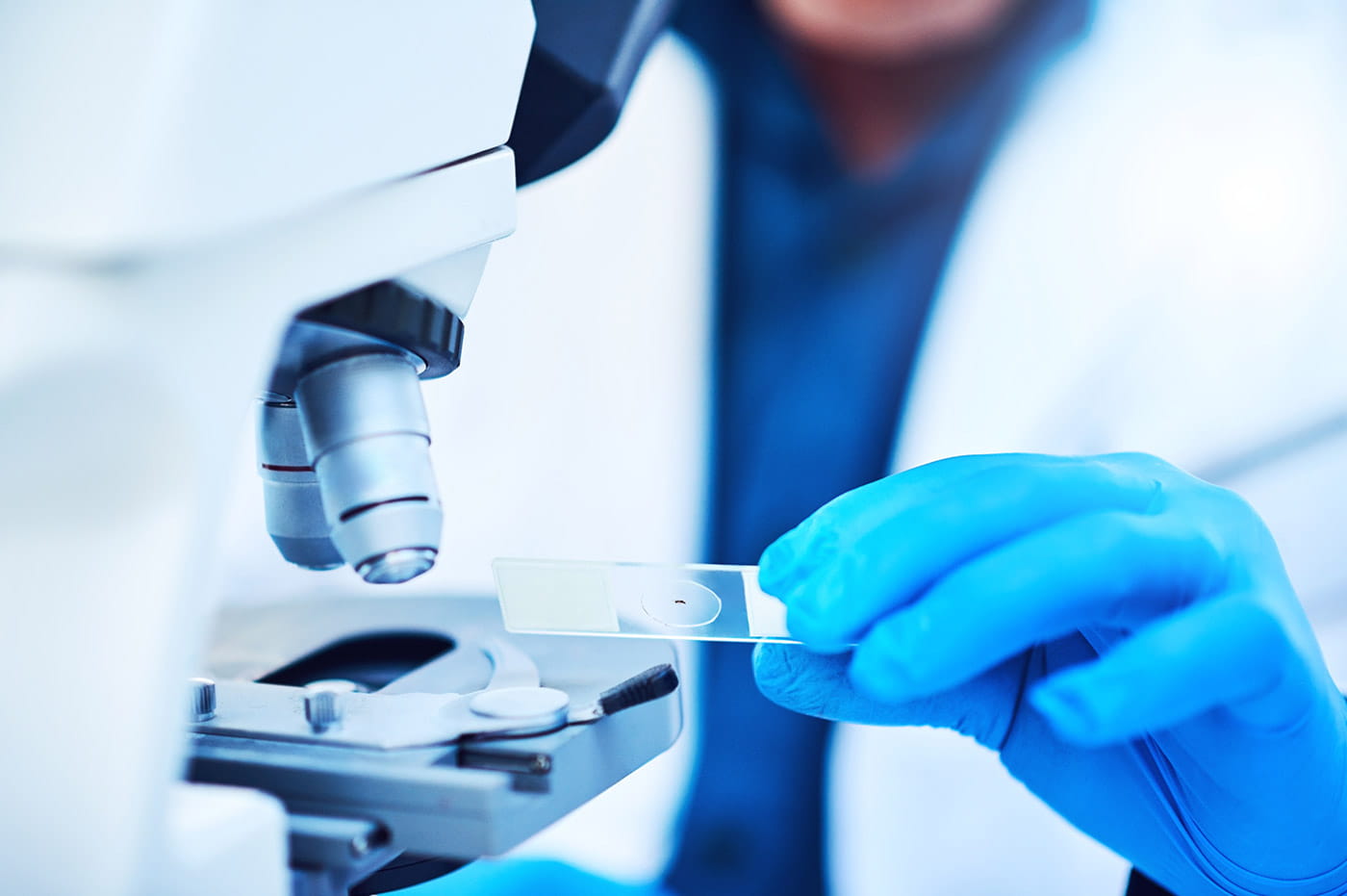 A doctor inspecting a blood sample under a microscope.