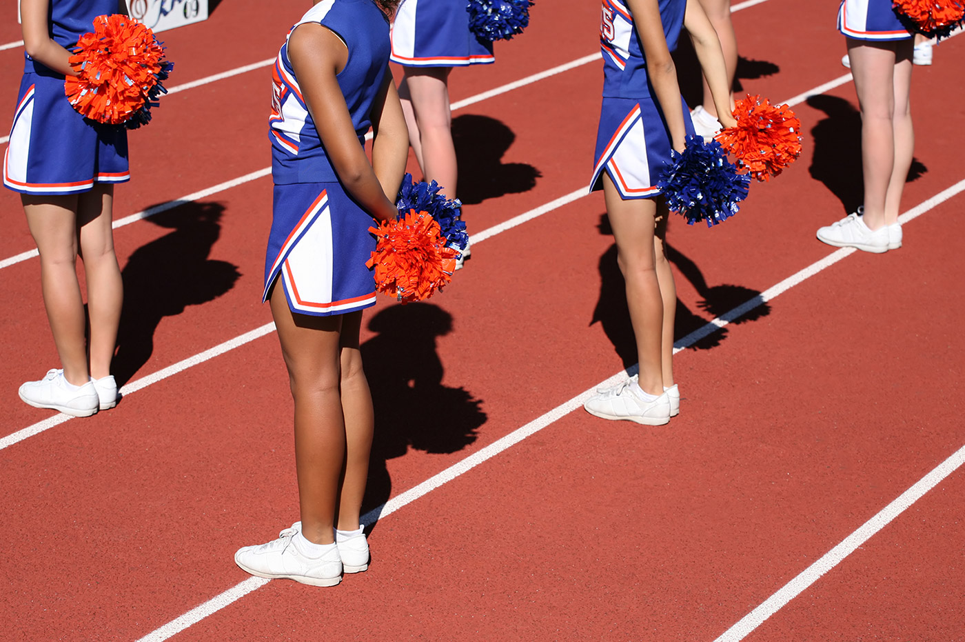 Several cheerleaders standing on a track.