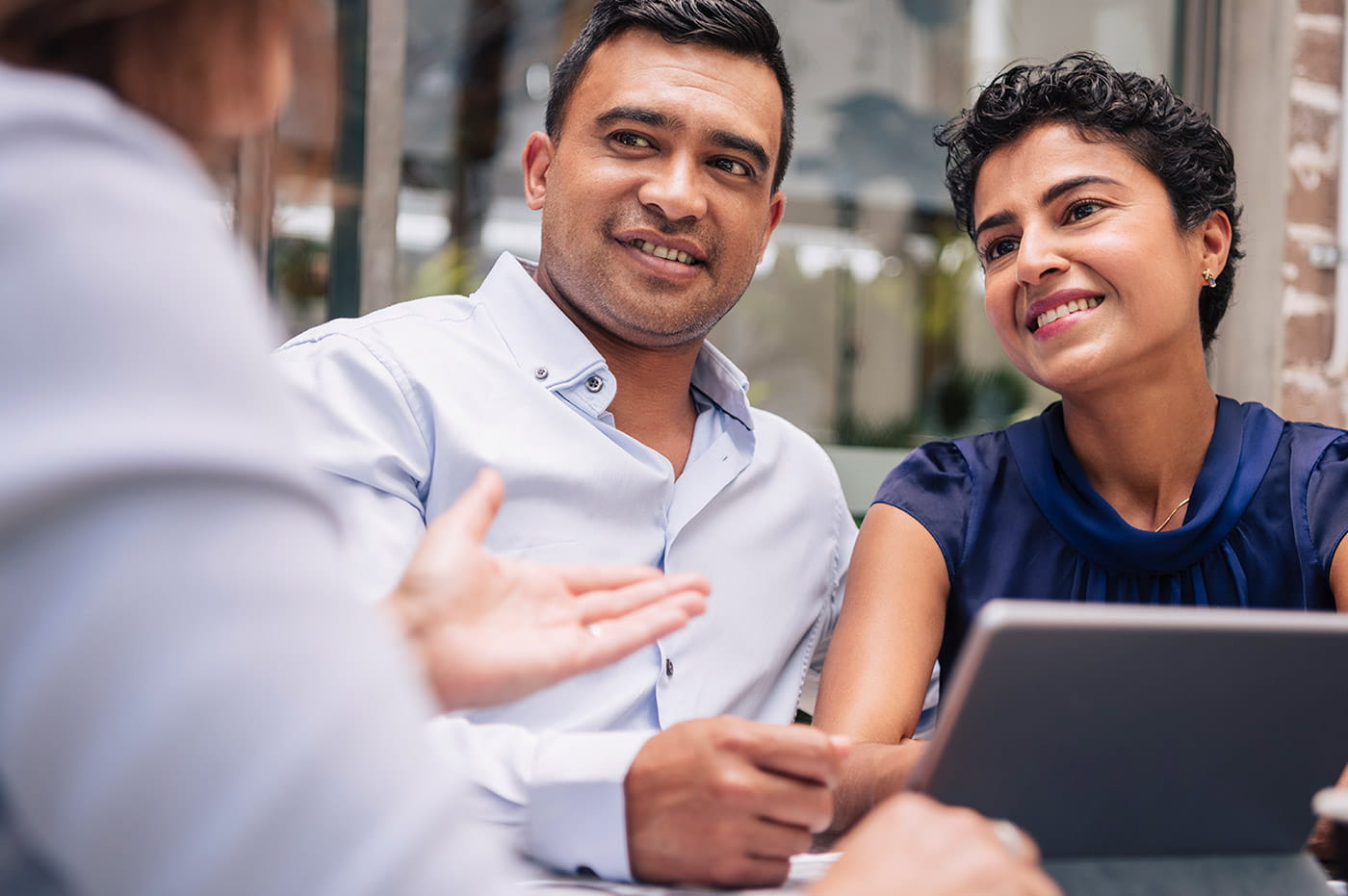 A couple looking at information on a tablet that a business person is holding.