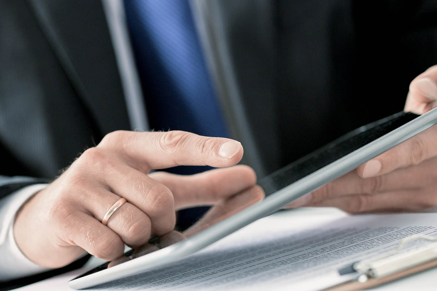 A man's hand typing something on a tablet.