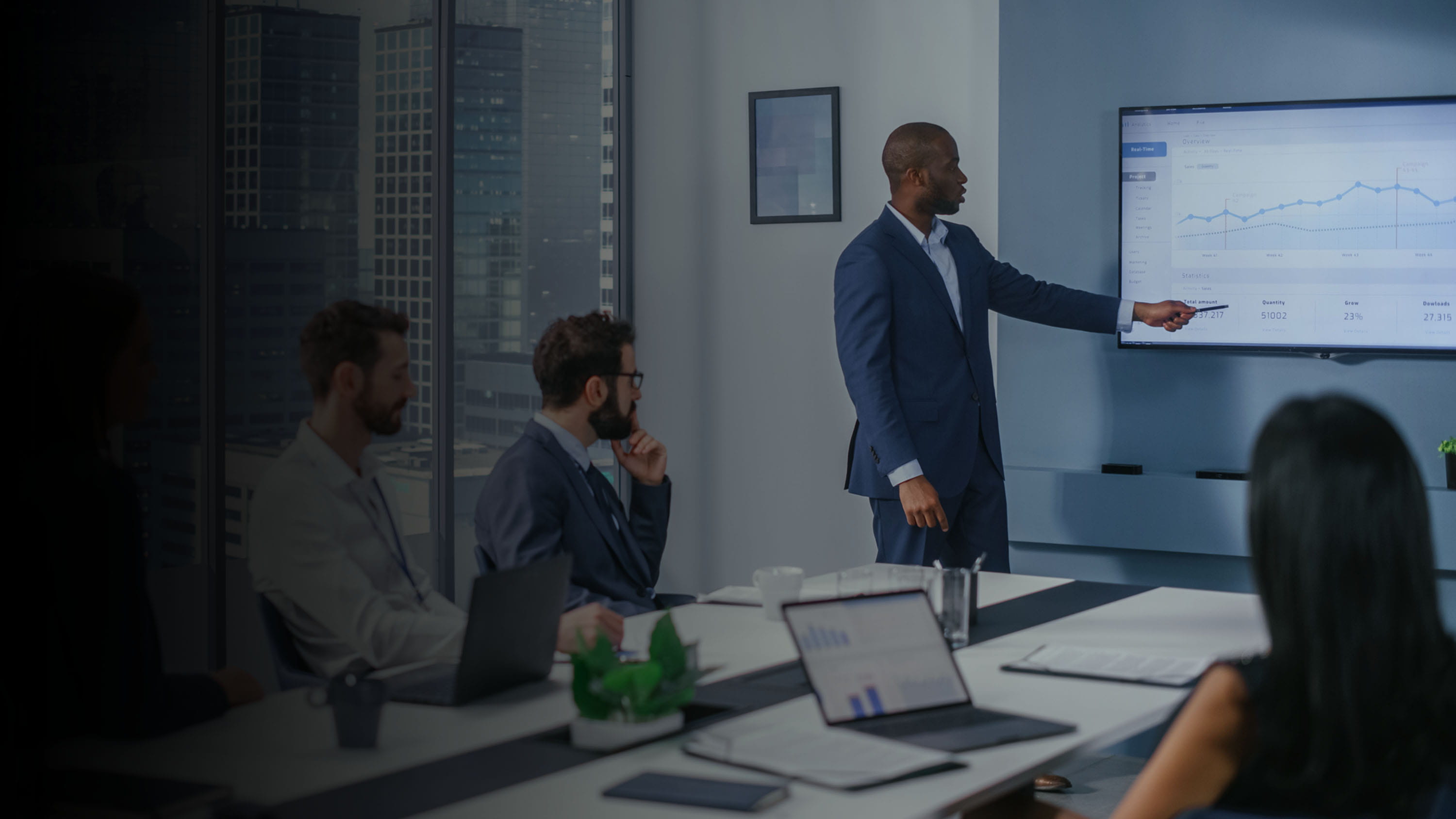 Meeting in an office space with a person pointing at a screen 