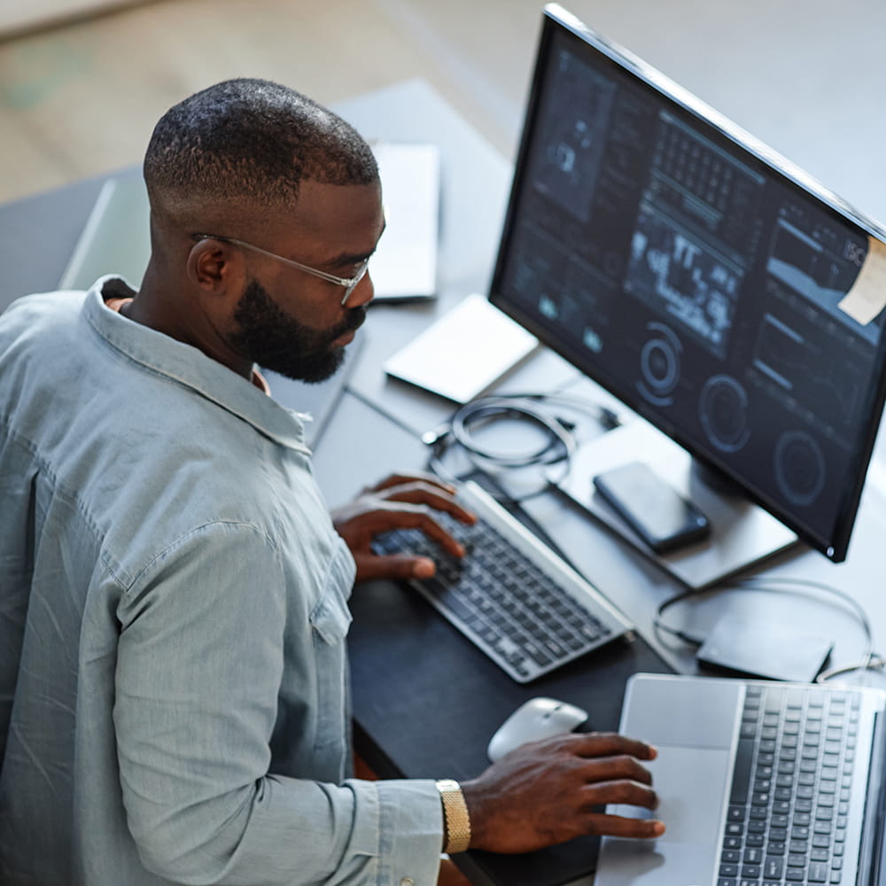 Man working at a desk with a big computer screen
