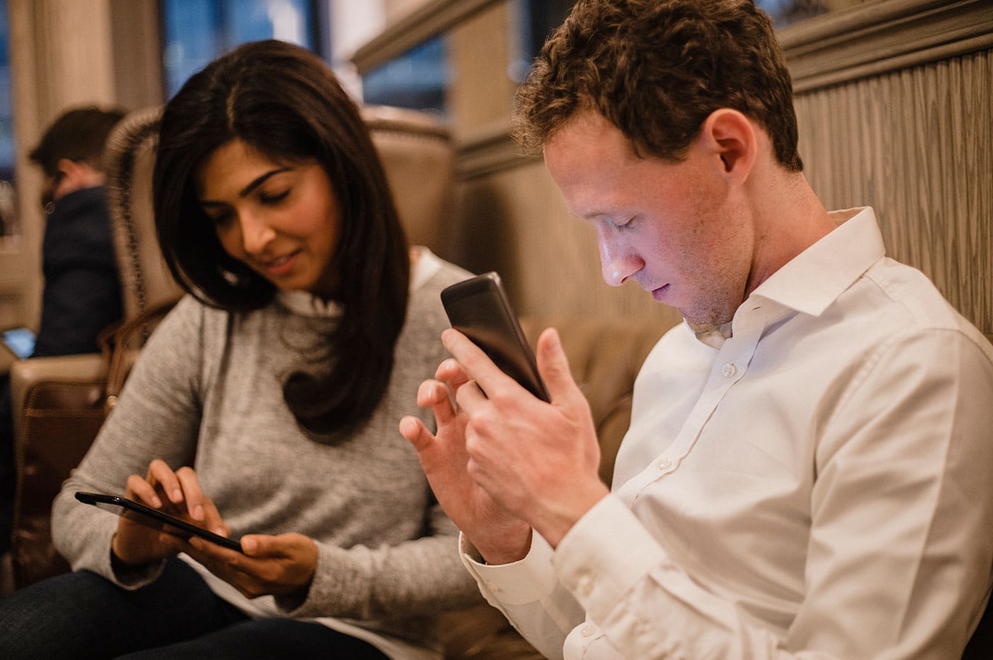 A man and woman working on their cellphones.