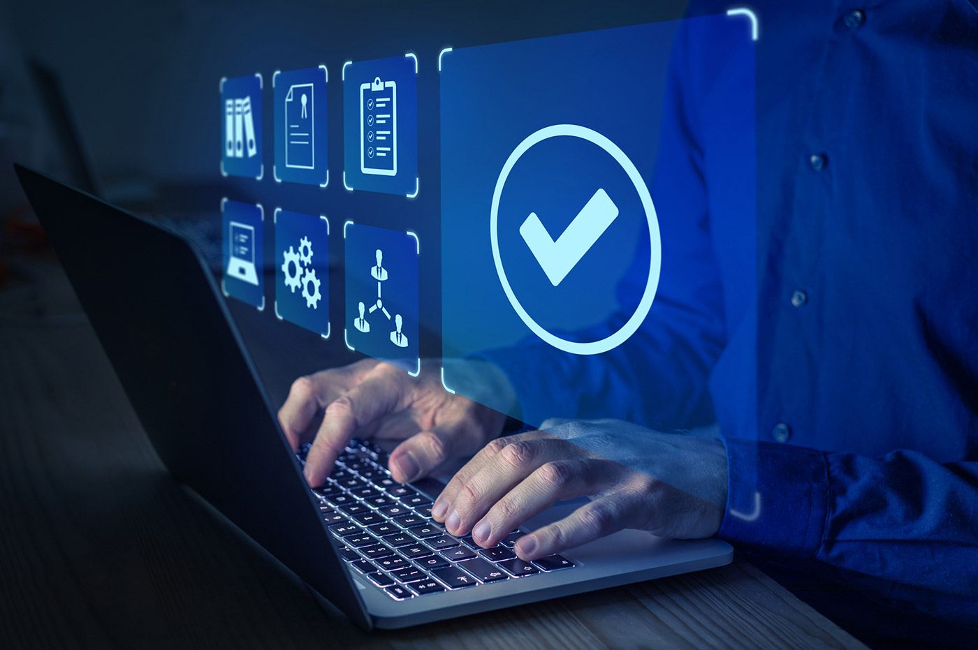 A man typing on a keyboard with holographic technology symbols floating over it. 