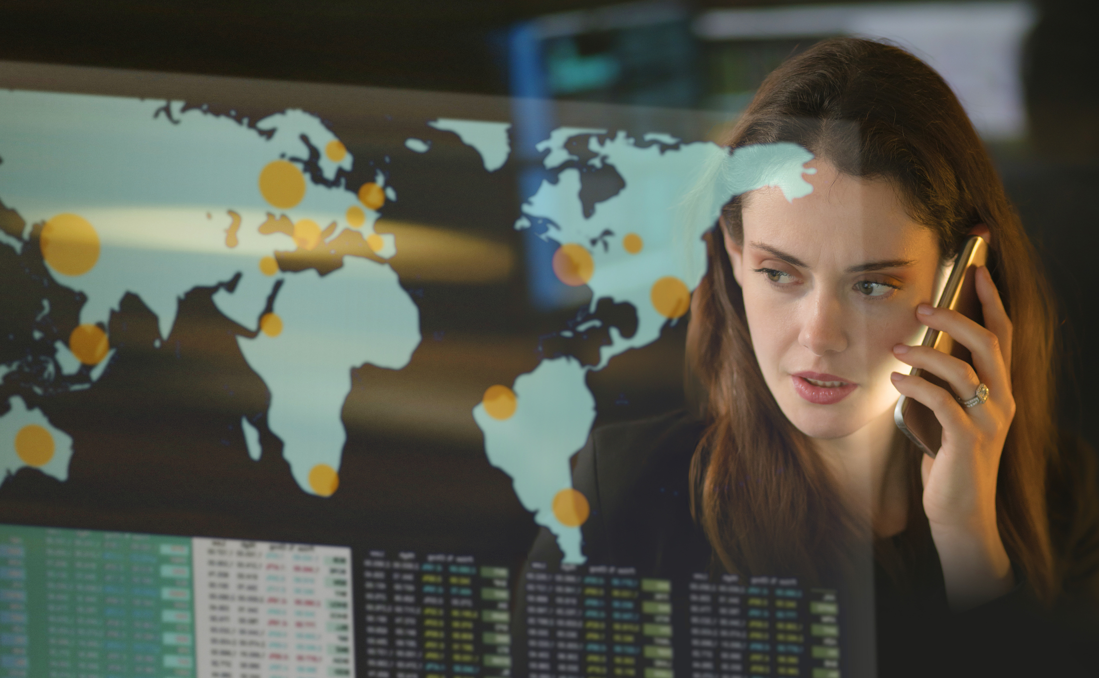 A woman looking at a digital global map and talking on the phone.