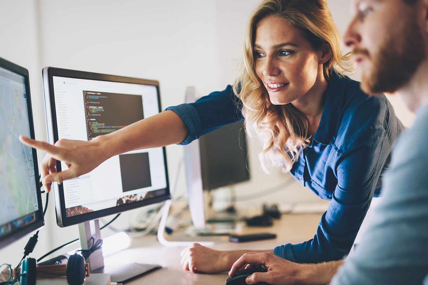 Two colleagues collaborating on a computer screen.