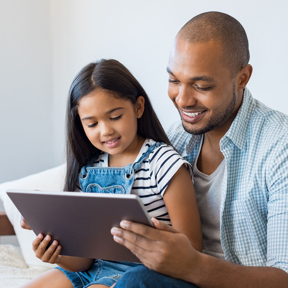 A father and daughter looking at a tablet together.