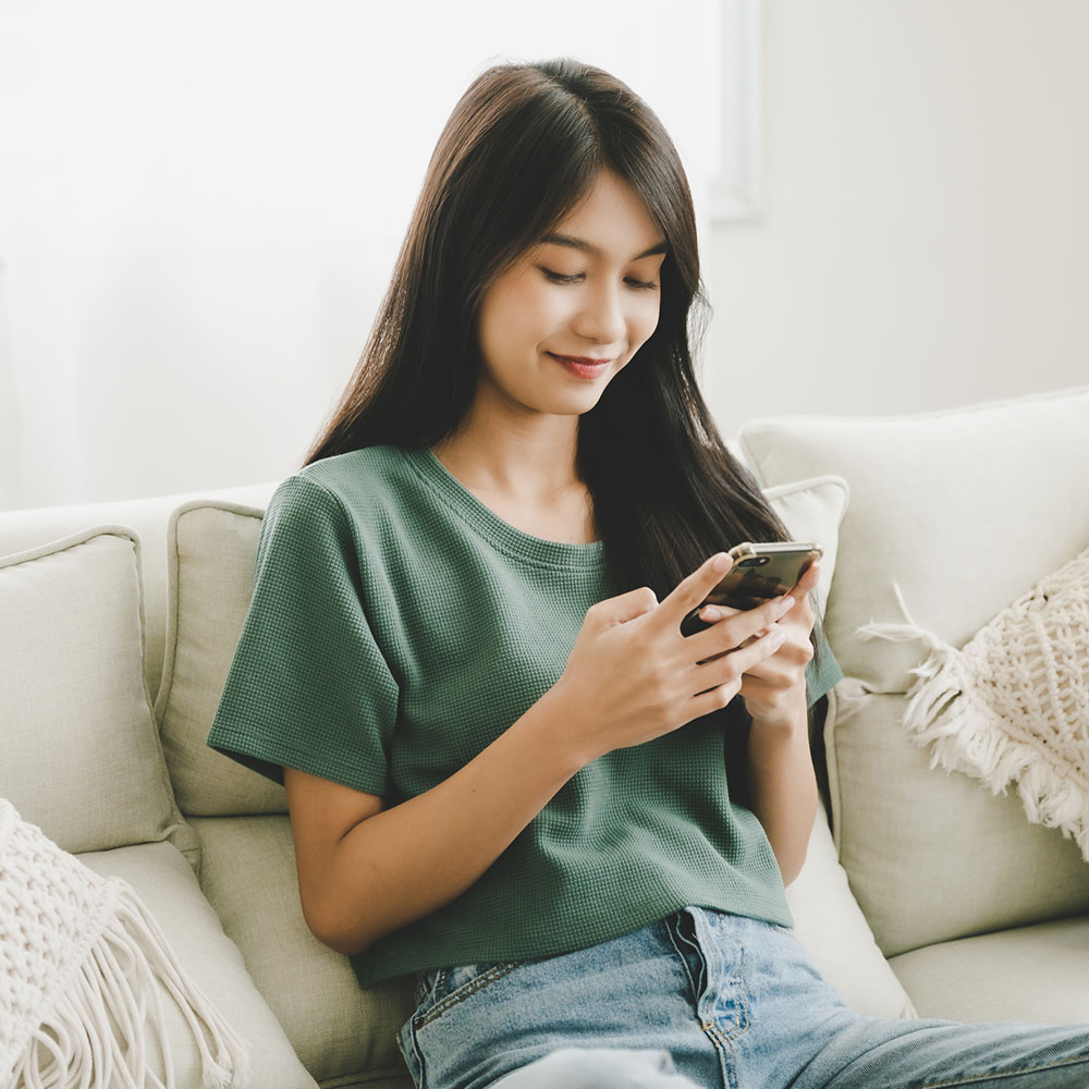 Woman sitting on a couch looking at her cellphone. 
