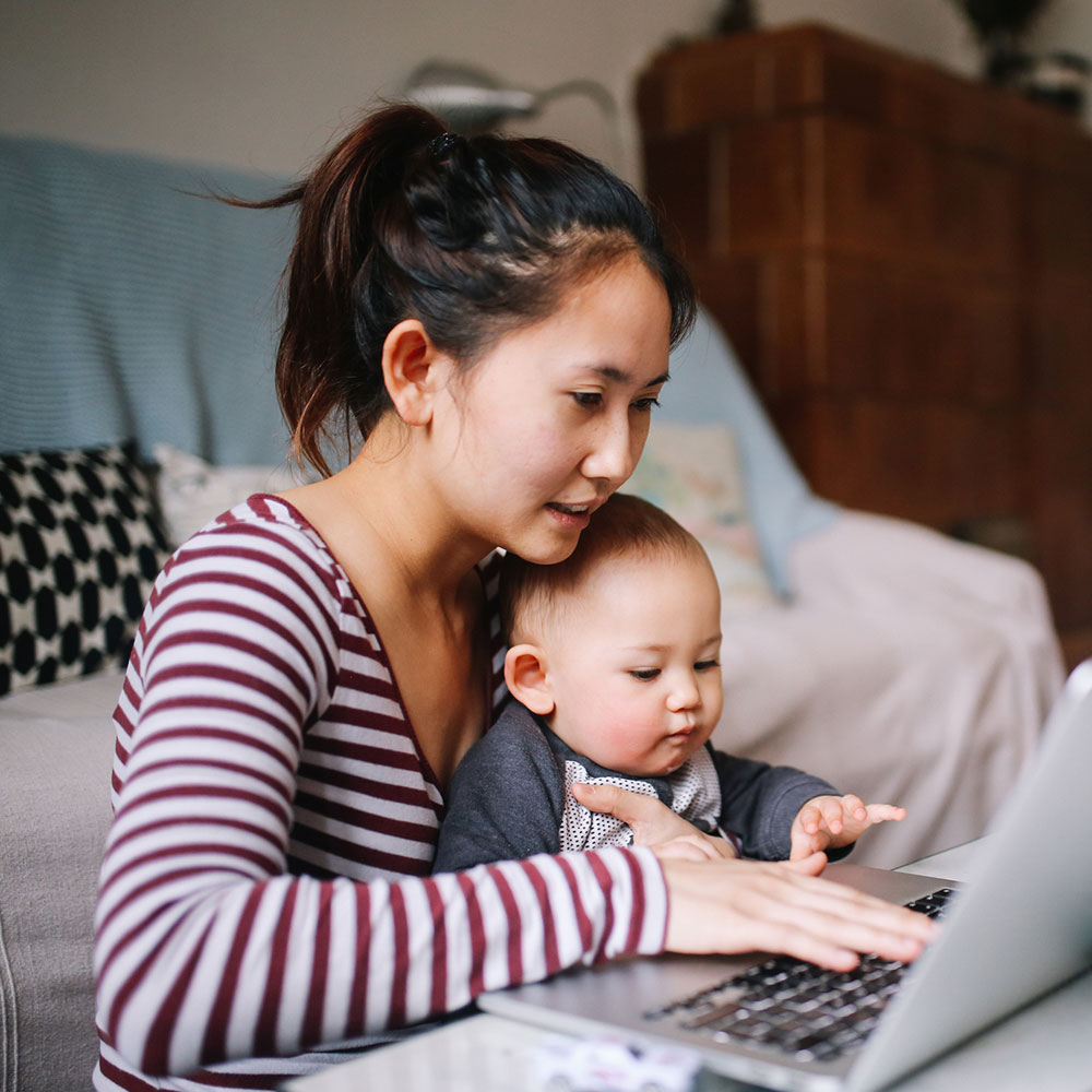 A woman with her baby looking at a computer.