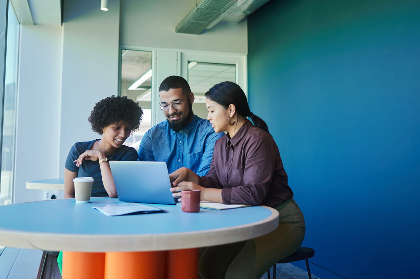 Three people gathered around a laptop.