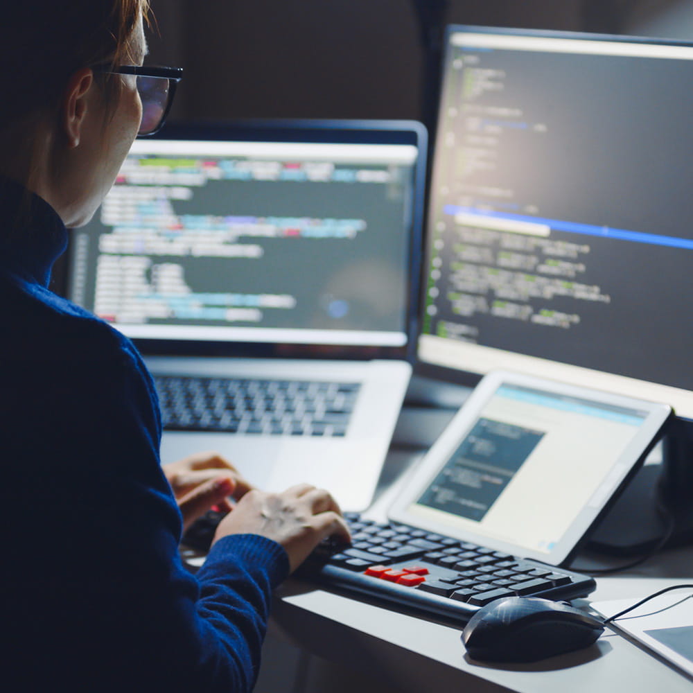 A web developer working on multiple computer screens.