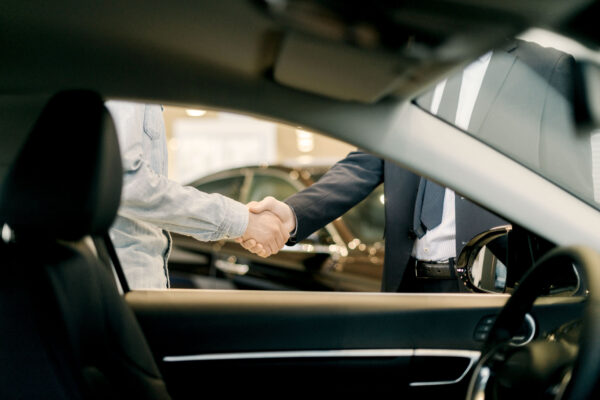 Two people shaking hands at a car dealership