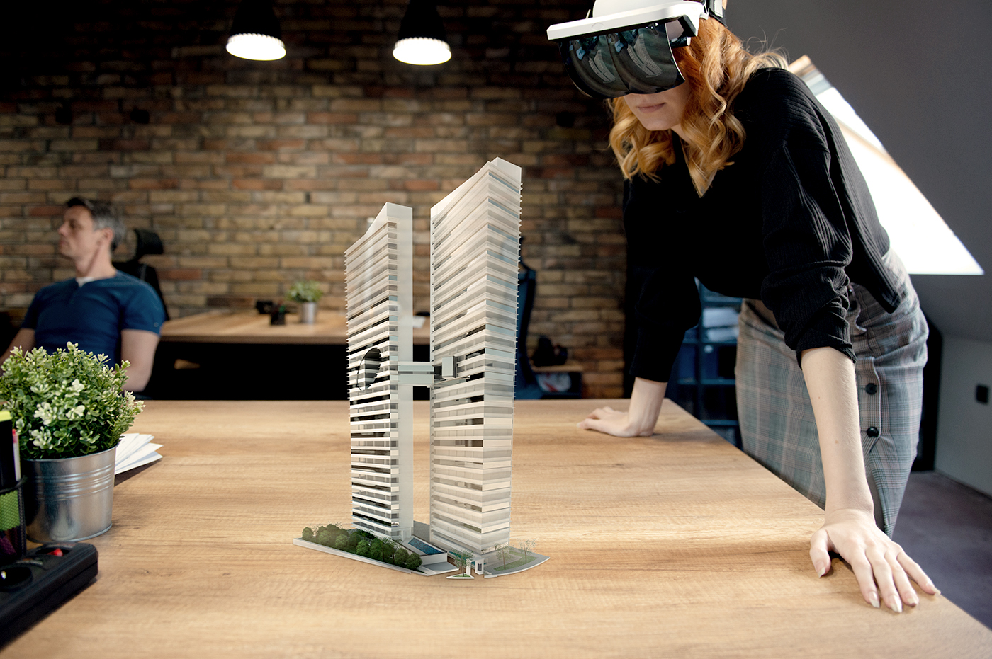 A woman using a virtual reality headset while looking at a model of a building.
