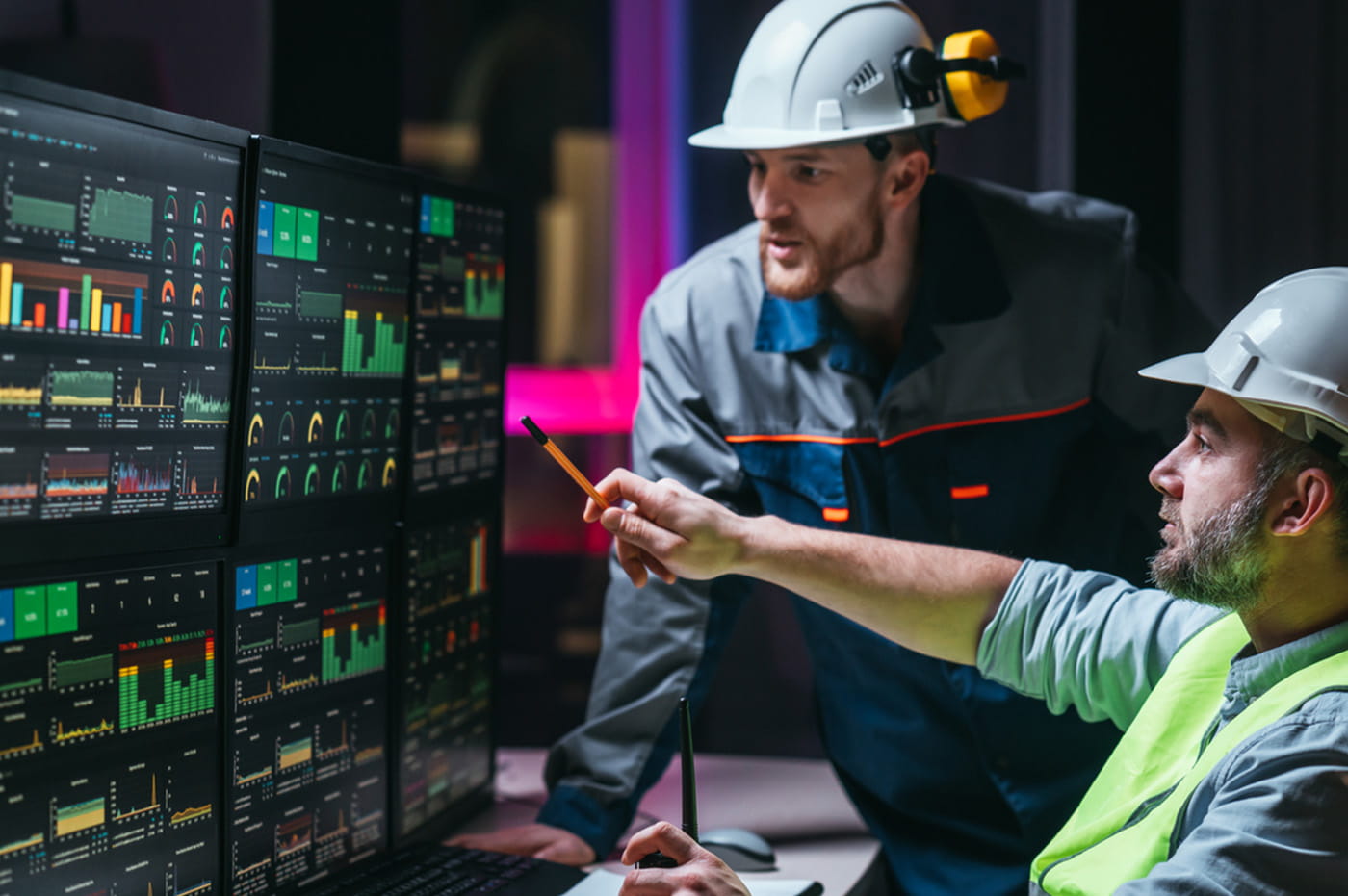 Construction works looking at charts on multiple computer screens