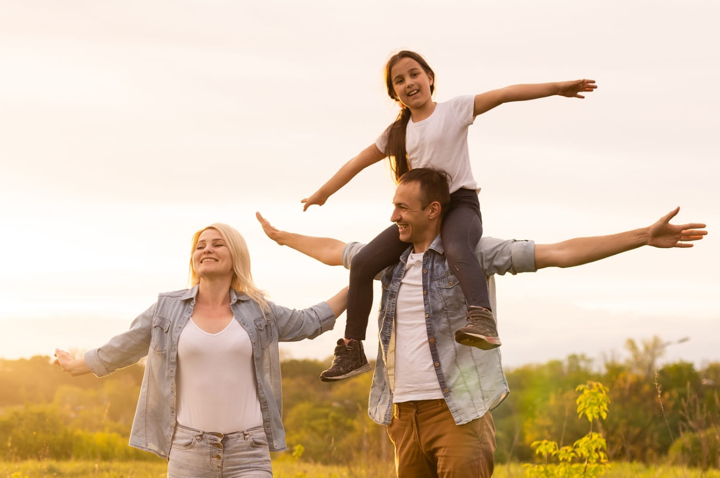 Woman, Man with child on top of his shoulders all standing with their arms open. 