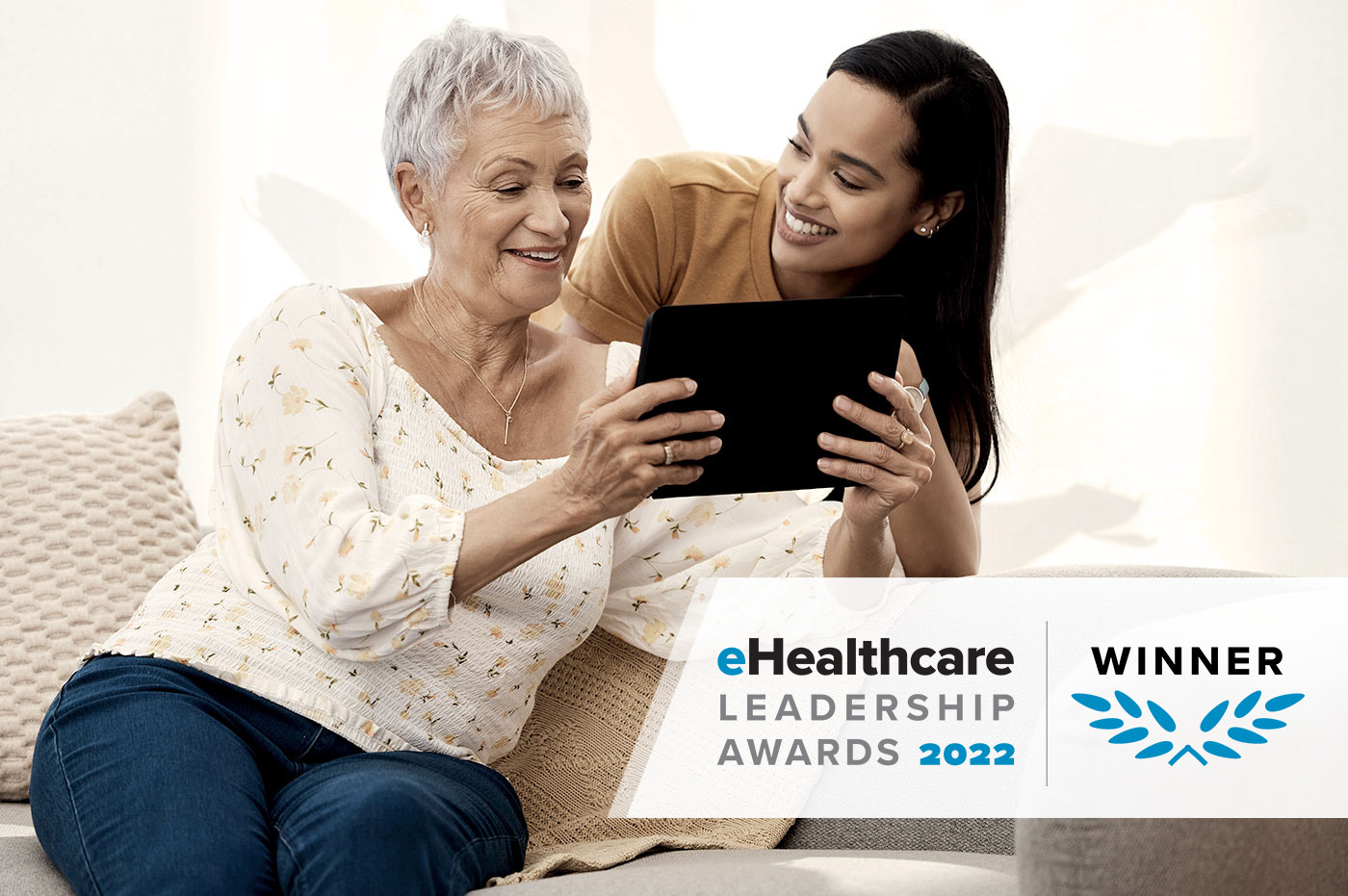 A healthcare worker and older woman looking at a tablet. EHealthcare leadership awards badge in corner.