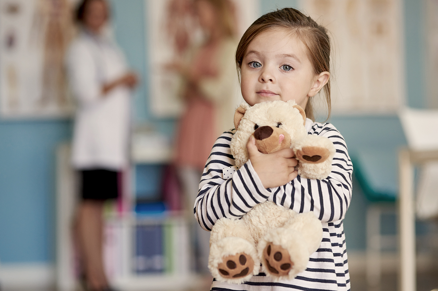 A little girl hugging her teddy bear.