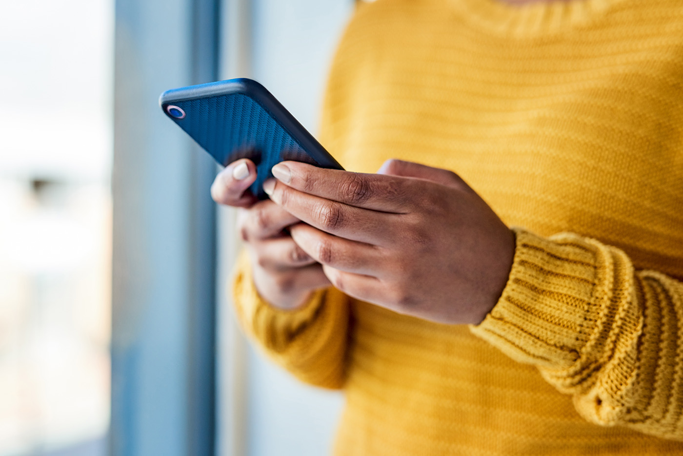 A person in a yellow sweater texting